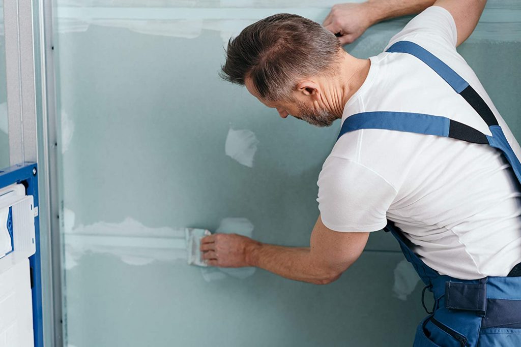 Homme qui rénove un mur abimé