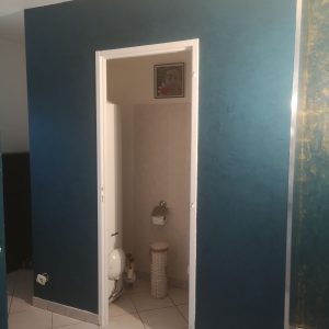 Mur bleu vert avec un petit panier blanc dans une petite salle